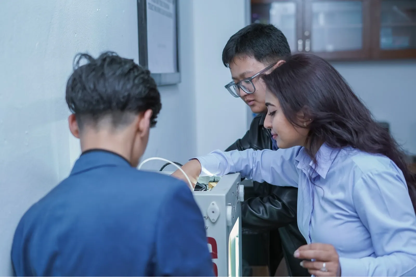Two boys and a girl playing with lab machine