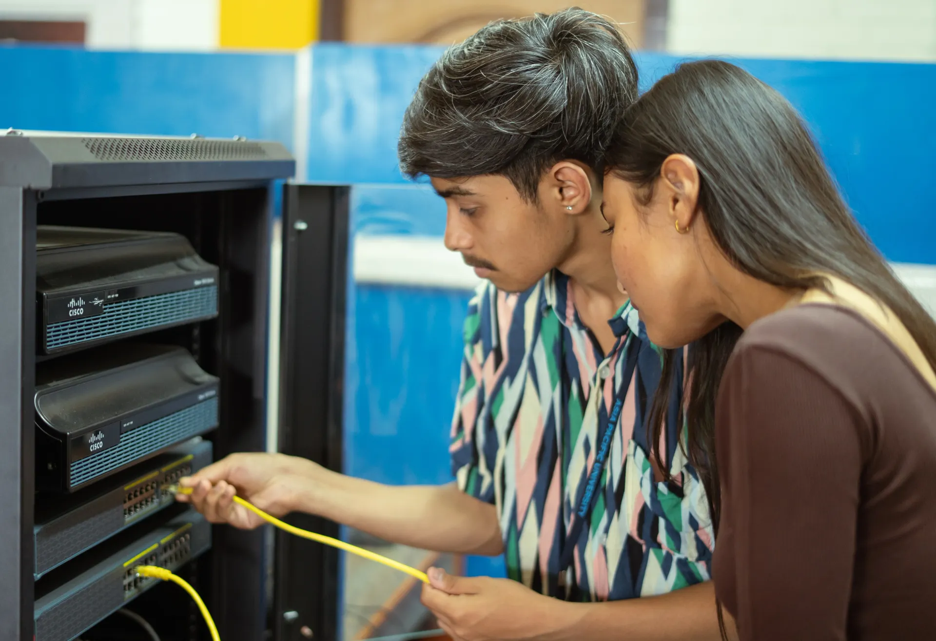 Students in computer lab with teacher providing guidance