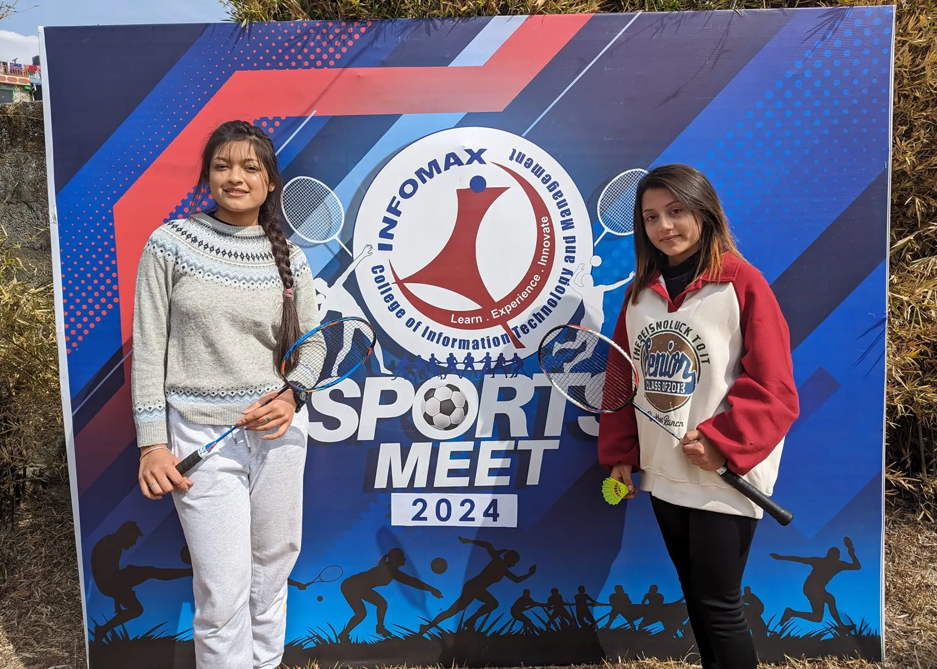 Two girl holding badminton and standing side by side